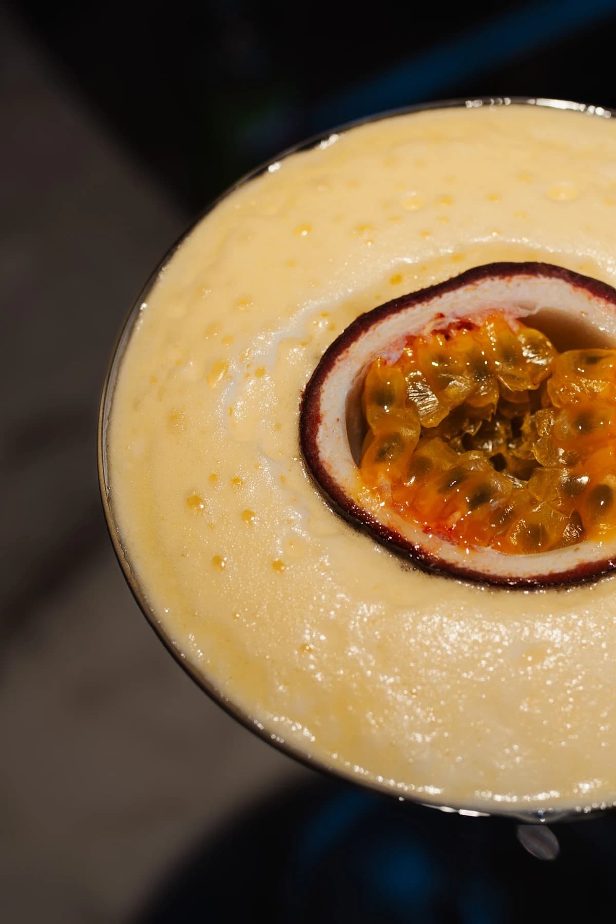 Een halve passievrucht op de romige schuimlaag van een cocktail bij ChouChou.