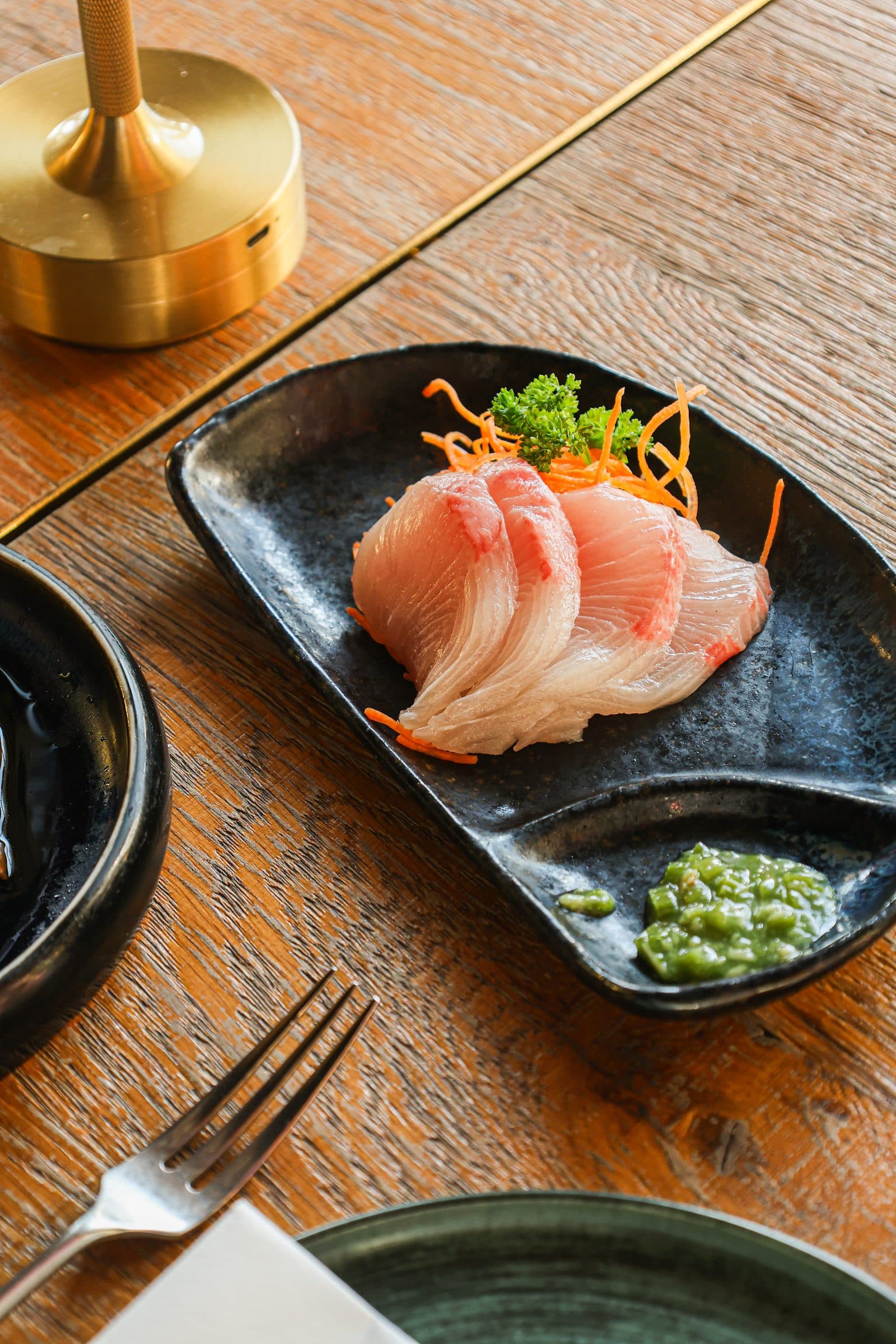 Sashimi op een zwart bord in warm zonlicht bij ChouChou.