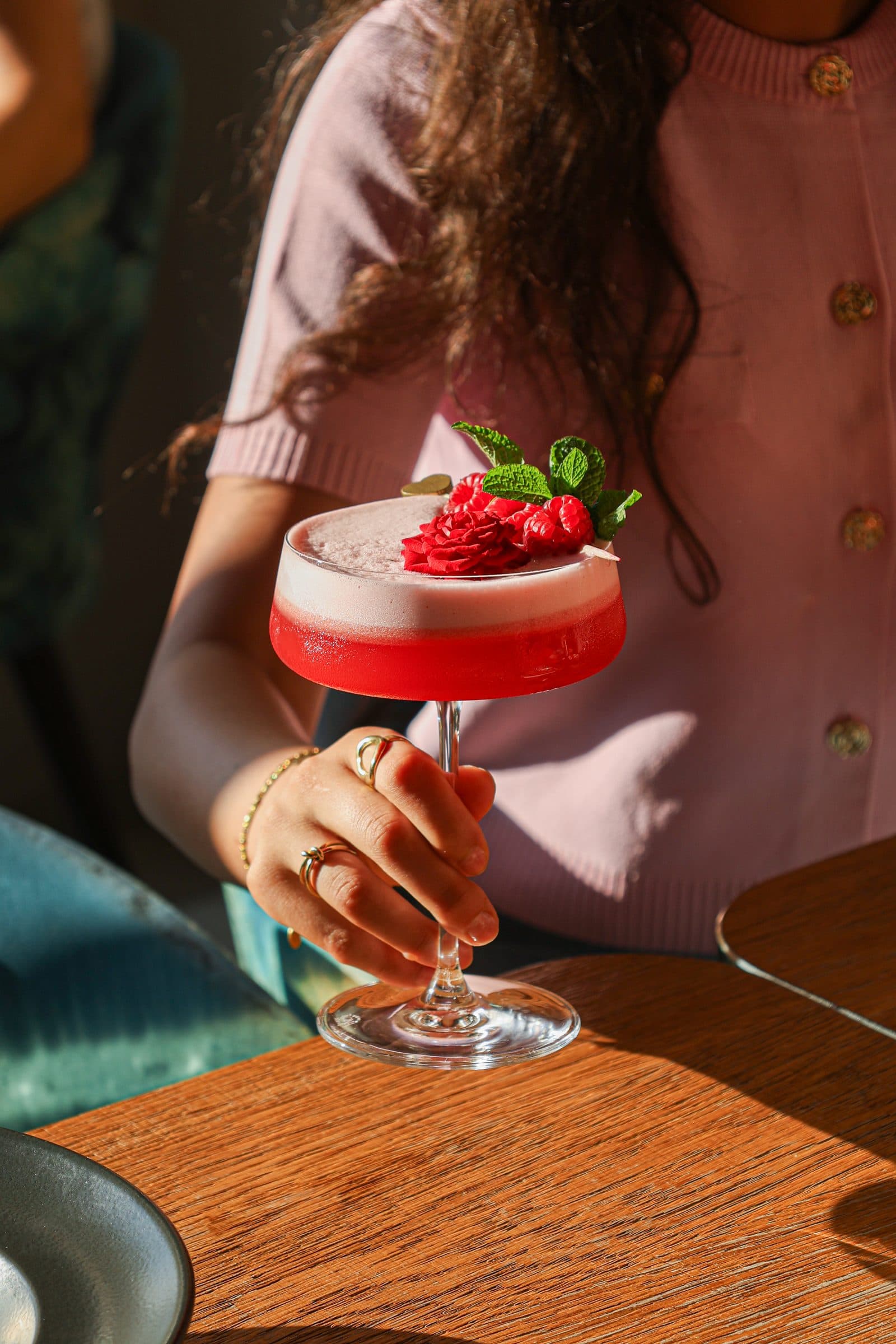 Een gast houdt een rode cocktail met schuim en bessen vast bij ChouChou.