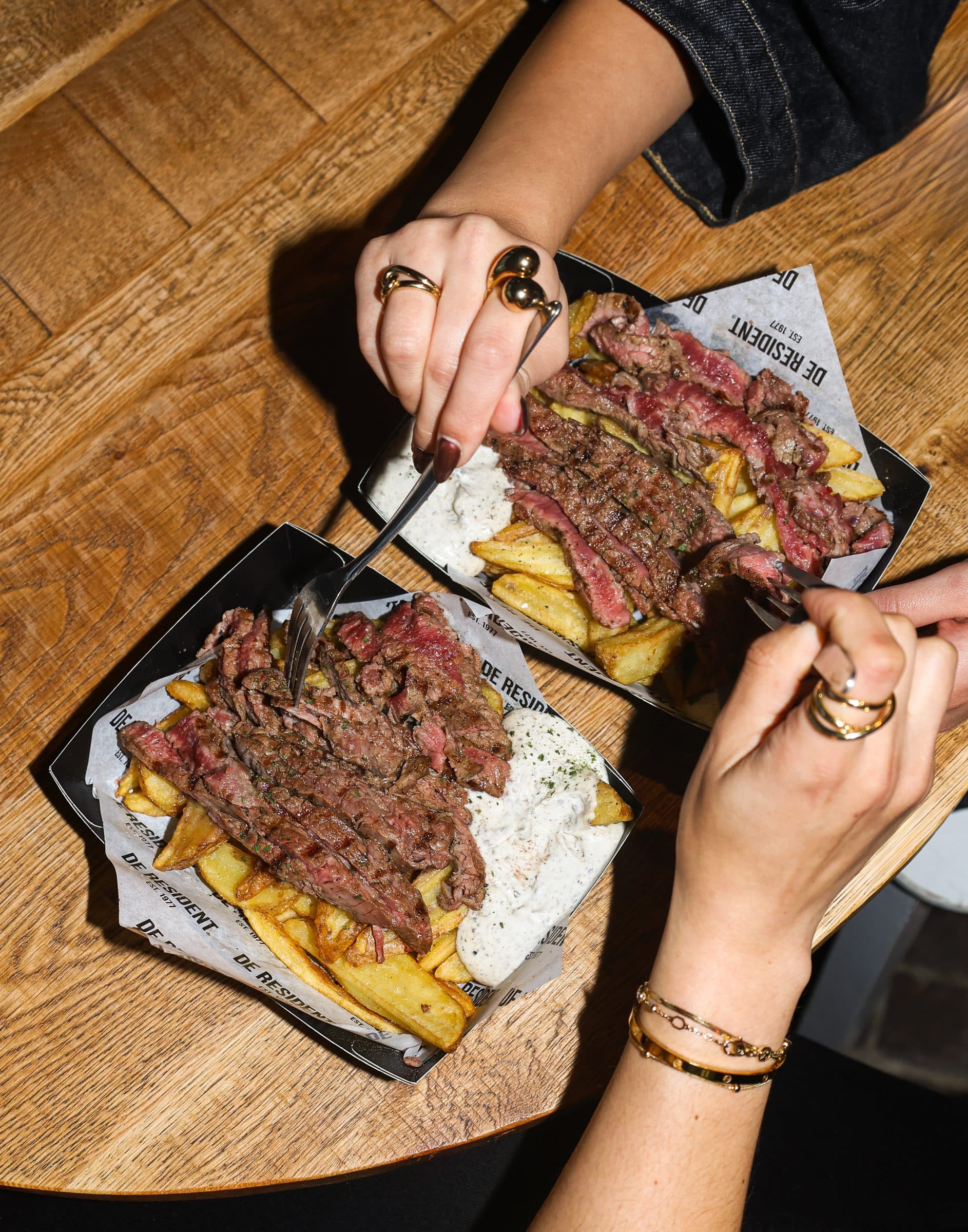 Van boven gefotografeerde steak en friet op een houten tafel bij Foodhall Scheveningen.
