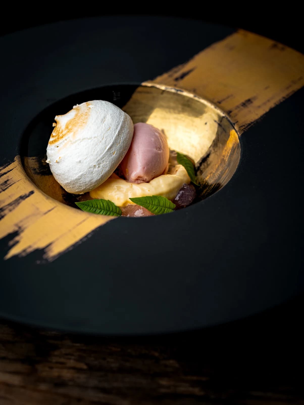 Een verfijnd dessert met een bolletje ijs in een zwarte en goudkleurige presentatie bij Landgoed Groenendaal in Heemstede.