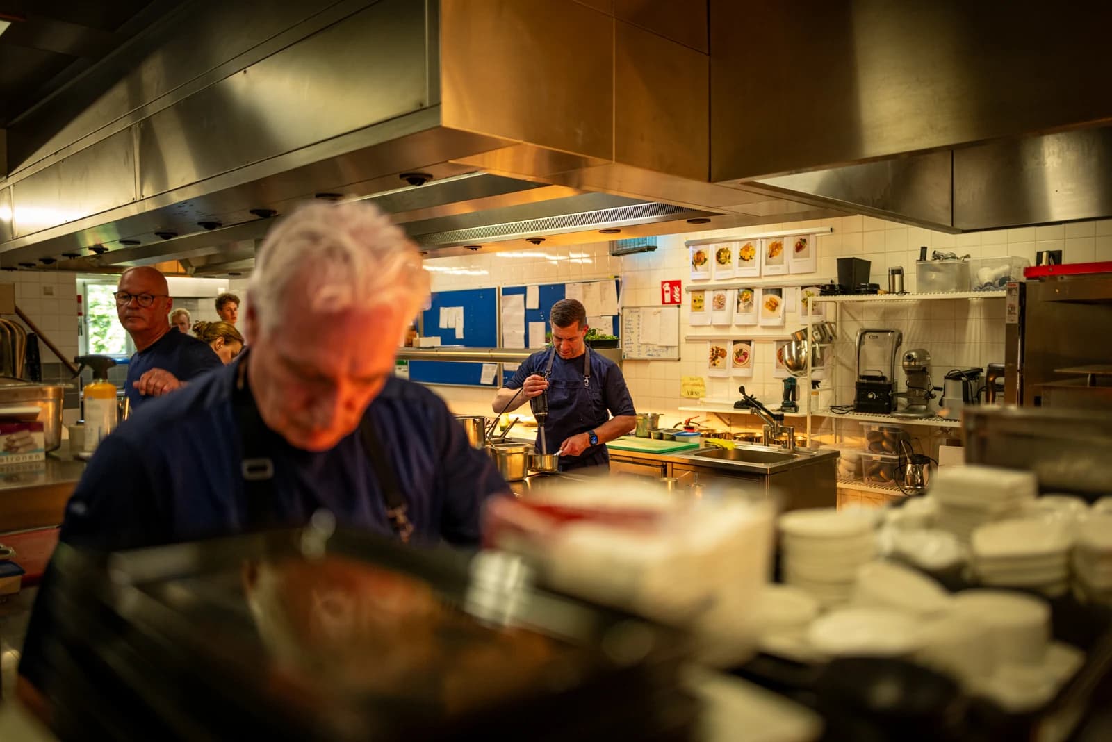 Het keukenteam van Landgoed Groenendaal aan het werk achter stapels borden in warm licht.