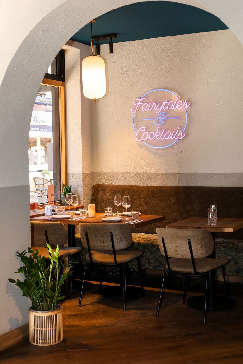 Gedekte tafels onder een lichte boog en het neonopschrift Fairytales & Cocktails bij Lavash.